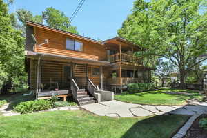 Rear view of the property with walkout basement, covered porch, balcony, and a lawn