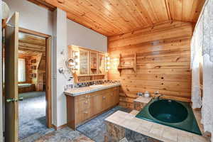 Primary bathroom featuring wood walls, vanity, tile patterned floors, and wooden ceiling