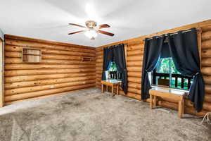 Bedroom featuring ceiling fan, carpet flooring, and rustic walls