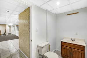 Bathroom with vanity, tile patterned flooring, a drop ceiling, and toilet