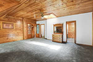 Primary bedroom with a skylight, ceiling fan, carpet floors, and wooden ceiling