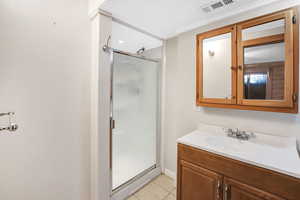 Bathroom featuring walk in shower, tile patterned flooring, and vanity