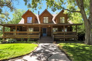 Log cabin featuring covered porch and a front lawn