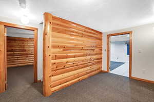 Corridor featuring a textured ceiling, carpet, and rustic walls