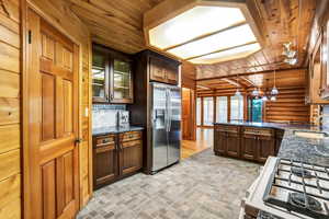 Kitchen featuring decorative backsplash, wooden ceiling, hanging light fixtures, and stainless steel fridge