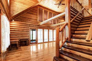 Staircase featuring light hardwood / wood-style floors, high vaulted ceiling, log walls, and wood ceiling