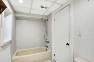 Bathroom with tile patterned flooring, toilet, and tiled shower / bath combo