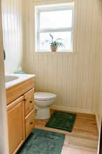 Bathroom featuring hardwood / wood-style flooring, a healthy amount of sunlight, toilet, and vanity