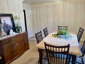 Carpeted dining space featuring ornamental molding