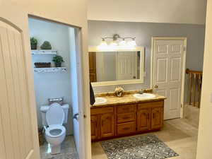 Primary Bathroom featuring toilet, tile patterned flooring, and dual bowl vanity