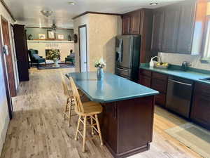 Kitchen featuring light hardwood / wood-style flooring, stainless steel appliances, a breakfast bar, a center island, and ceiling fan