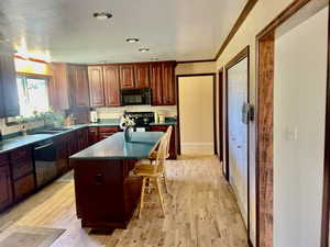 Kitchen featuring light wood-type flooring, dishwasher, a kitchen island, electric range oven, and sink