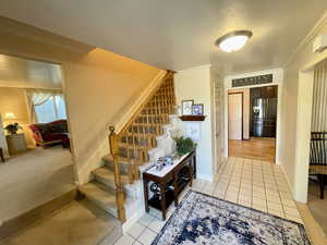 Foyer entrance featuring ornamental molding and light colored carpet