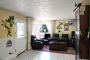 Living room with tile patterned floors, a textured ceiling, and a wealth of natural light