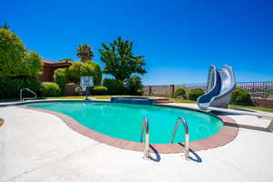 View of pool featuring a water slide and an in ground hot tub