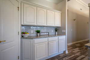 Kitchen with dark hardwood / wood-style flooring, dark stone countertops, and tasteful backsplash