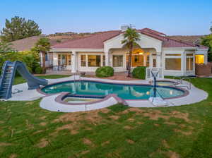 View of pool featuring a water slide, a patio area, an in ground hot tub, and a yard