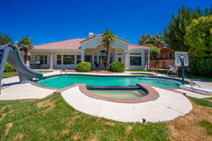 View of swimming pool featuring an in ground hot tub, a water slide, and a patio area