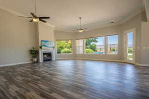 Unfurnished living room with ceiling fan, plenty of natural light, and dark wood-type flooring