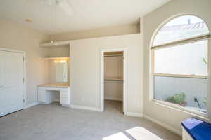 3rd Bedroom featuring a closet, light colored carpet, built in desk, a walk in closet, and ceiling fan