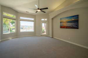 Carpeted empty room with ceiling fan and lofted ceiling