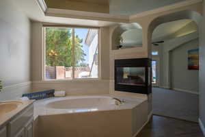 Bathroom featuring a washtub, a tile fireplace, a wealth of natural light, and vanity