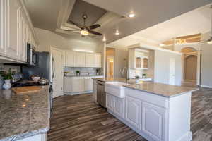 Kitchen with a tray ceiling, white cabinetry, dark hardwood / wood-style floors, and ceiling fan