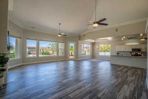 Unfurnished living room with crown molding, lofted ceiling, dark hardwood / wood-style flooring, and ceiling fan