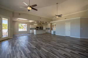 Unfurnished living room featuring dark hardwood / wood-style flooring, ceiling fan, and ornamental molding