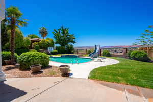 View of swimming pool featuring a patio, a water slide, and a yard