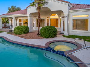 Rear view of property featuring a patio and a swimming pool with hot tub