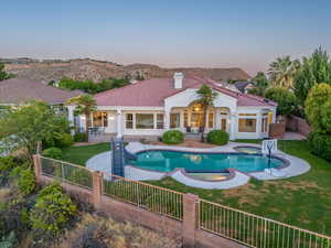 Pool at dusk with a mountain view, an in ground hot tub, a patio area, and a yard