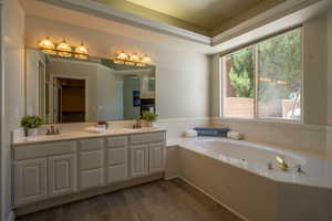 Bathroom with wood-type flooring, double sink vanity, and a bathing tub