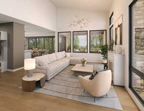 Living room featuring a high ceiling, a chandelier, and light hardwood / wood-style floors