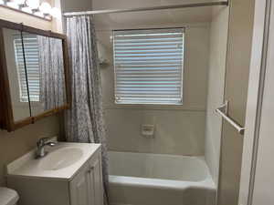 Full bathroom with vanity, shower / tub combo with curtain, and toilet