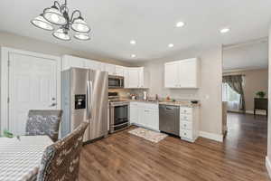 Kitchen featuring white cabinets, dark wood-type flooring, appliances with stainless steel finishes, and sink