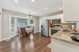 Kitchen featuring white cabinetry, light stone counters, dark hardwood / wood-style flooring, appliances with stainless steel finishes, and sink