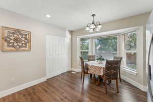 Dining space featuring an inviting chandelier, dark hardwood / wood-style floors, and a healthy amount of sunlight