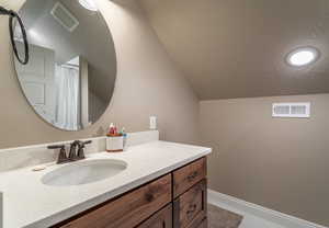 Bathroom featuring lofted ceiling and vanity