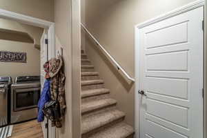 Stairway with washing machine and clothes dryer and hardwood / wood-style flooring