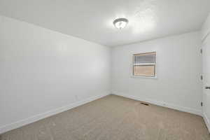 Empty room with carpet floors and a textured ceiling