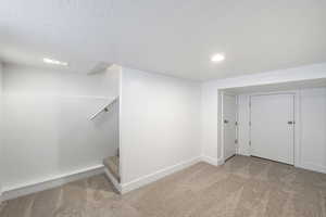 Basement featuring a textured ceiling and light colored carpet