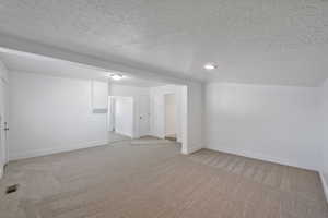 Additional living space with carpet floors and a textured ceiling