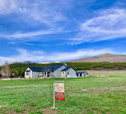View of front facade featuring a rural view, a front lawn, and a mountain view