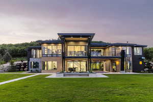 Rear view of house featuring a balcony, a yard, and a patio