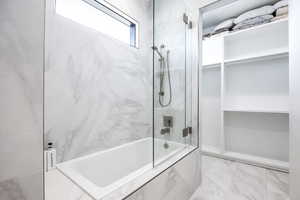 Full bathroom with a combined bath / shower with marble appearance, a skylight, and marble look tile flooring