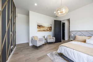 Bedroom with a chandelier, light wood-style floors, baseboards, and recessed lighting