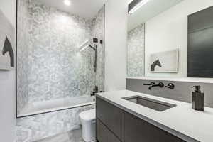 Full bath featuring tiled shower / bath combo, toilet, vanity, and tile patterned flooring