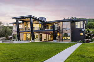 Back of property at dusk with a balcony, stairway, a yard, and a patio