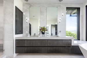 Bathroom with a soaking tub, double vanity, and tile walls